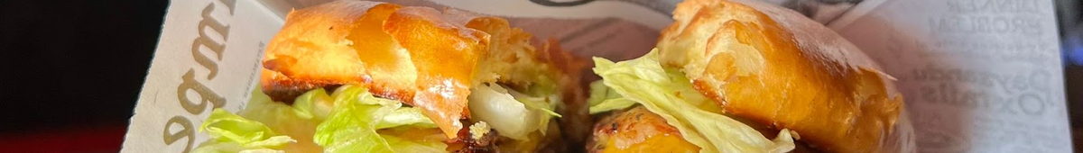Hamburguesa cortada con la salsa a la vista, junto al rótulo del local